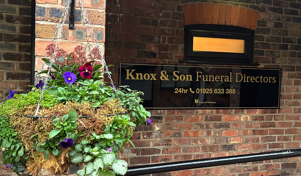 Knox and Son funeral directors sign with hanging flower basket
